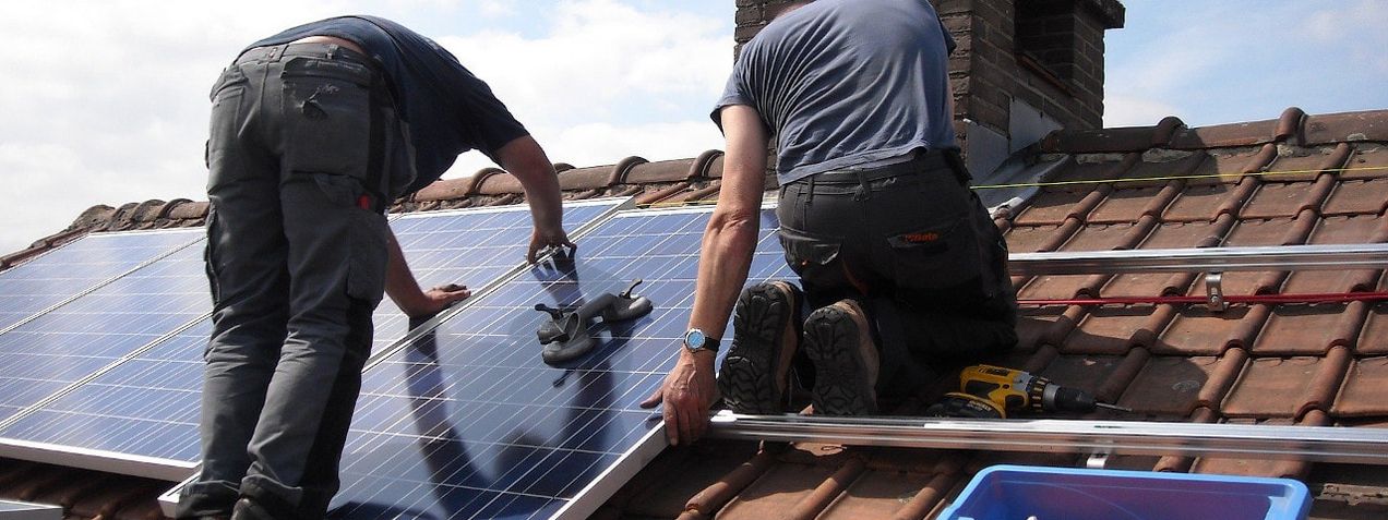 Image of workers installing solar panels on a roof