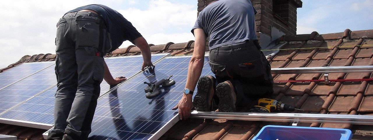 Image of workers installing solar panels on a roof